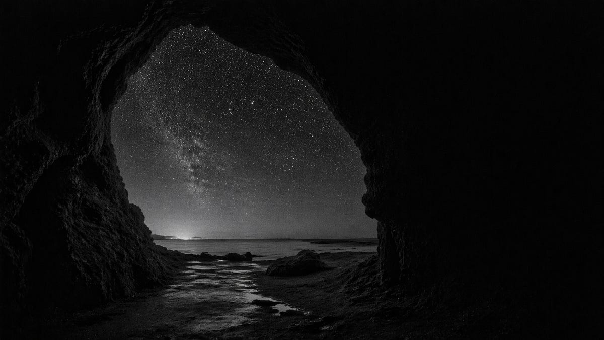 A cave mouth opening onto a starlit sea at night
